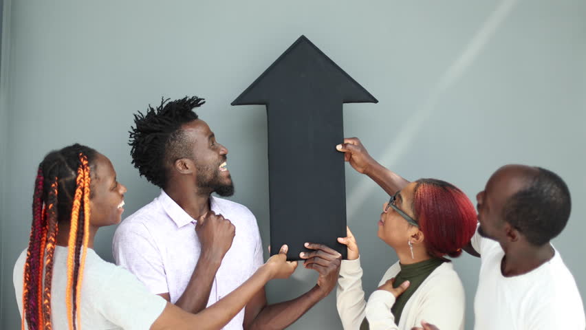 Positive corporate team holding a black arrow pointing up.