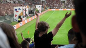 The silhouette of a teenage boy at a football match, he stands with his hands raised and claps. Football fans in crowded stands. - Powered by Shutterstock - Get 15% off with code: PIKWIZARD15