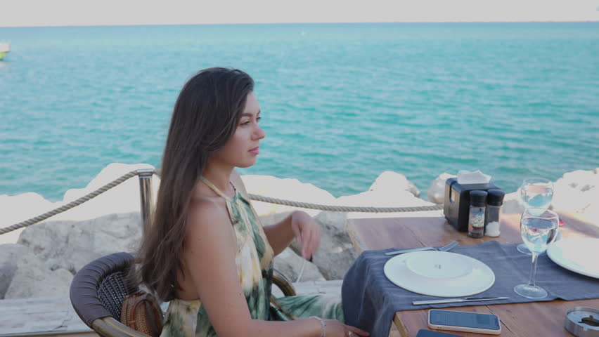 Young woman on holiday vacation enjoy her dinner in beachfront restaurant on pier with sea background.
