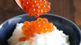 A close-up video of putting salmon roe on hot rice.