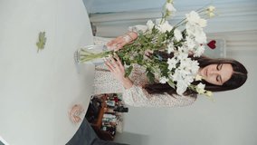 beautiful European girl with a vase and flowers in her hands, vertical video