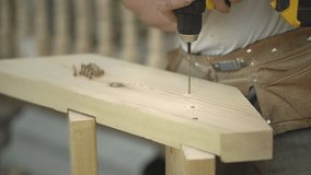 wood processing. a man with a tool twists a self-tapping screw into a board. assembling assembling stairs made of wood. slow motion video. High quality Full HD video recording