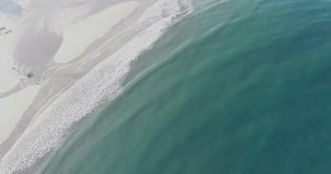 aerial footage  with drone, descending view of the shore of a beach at sunrise