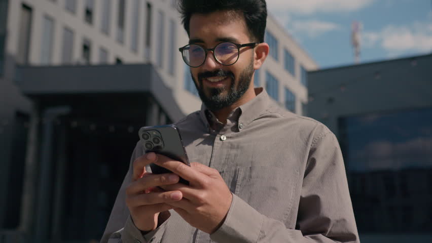 Indian Arabian man guy employer entrepreneur shock amazing read news on mobile phone winning online bet business achievement good job offer happy excited businessman in city outdoors celebrate victory Royalty-Free Stock Footage #1107068637