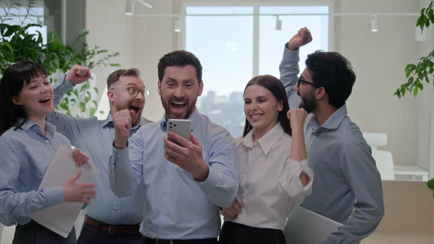 Successful group business people multiracial multinational office team colleagues happy excited businessmen businesswomen read good news on mobile phone celebrate winning commercial offer online bet Royalty-Free Stock Footage #1107068655