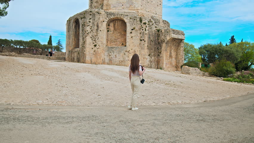 Beautiful girl takes pictures at Tour Magne in Nimes, France. 18m stone watchtower, part of the Roman city wall from the Augustinian era, with panoramic views.

