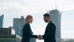 Side view two successful business partners male female handshaking meet and shake hands coming to each other on office building rooftop terrace overlooking high-rise skyscrapers modern city downtown - Powered by Shutterstock - Get 15% off with code: PIKWIZARD15