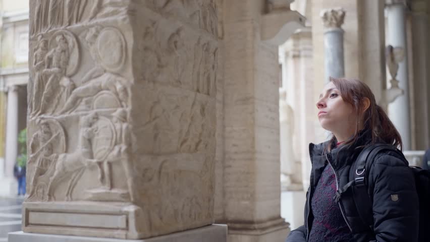 Contemplating Hispanic young woman in black jacket standing while walking ancient city in Vatican museum in Rome, Italy