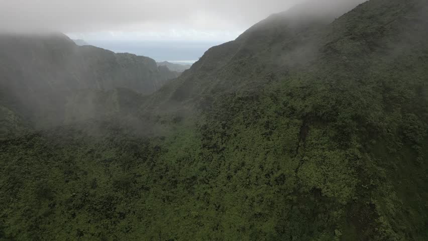 Mountain fog aerial flies over hikers descending ridge trail on Oahu
