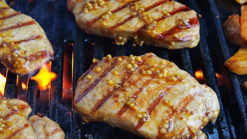 cooking pork loin chops and potatoes wedges on grill, barbecue, hot cast iron grate. close up. meat lubricate Dijon mustard Royalty-Free Stock Footage #1107099459