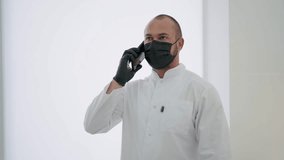 A doctor with a mask on his face is talking on the phone
