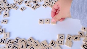 female hand close-up holds wooden alphabet blocks, makes up question marks from wooden letters on white background, dyslexia awareness, literacy problems, idea, human brain development concept - Powered by Shutterstock - Get 15% off with code: PIKWIZARD15