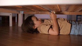 a little girl hides under the bed to play games on the phone