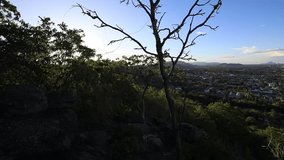 Natural video background of a high-angle atmosphere on a mountain that overlooks the surrounding scenery(mountains, trees,sea)from a scenic vantage point,with a wooden chair for sitting and resting