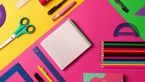 Stopmotion animation of composition of multi-colored stationery items laid out on the table. office, school FLAT LAY pink, yellow, green background. Copy space notebook. 4k footage, video, motion