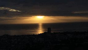 Natural video background of the morning sun shining in the middle of the sea, among the houses on the coast, seen from a vantage point on a high mountain while traveling.