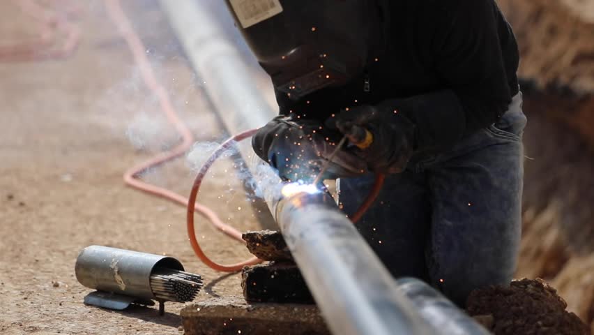 A man welder in uniform, welding mask, weld metal with a arc welding machine at the construction site, blue sparks fly to the sides Royalty-Free Stock Footage #1107111279