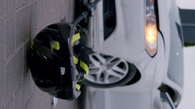 Close-up of a helmet spinning on the asphalt after a serious road accident from an electric scooter and a white luxury car in a residential area. The concept of road accidents.Vertical video for story