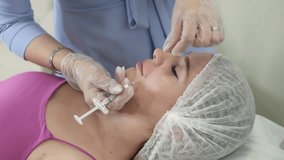 Practical application of a cosmetic procedure in the video: a dermatologist makes a collagen injection to eliminate wrinkles and rejuvenate the patient's face