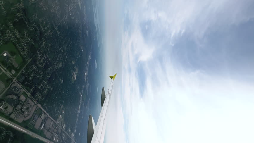 Timelapse. Vertical view through the passenger plane window of the long plane's wing, cityscape, white clouds, descending and landing in the city. Travelling concept