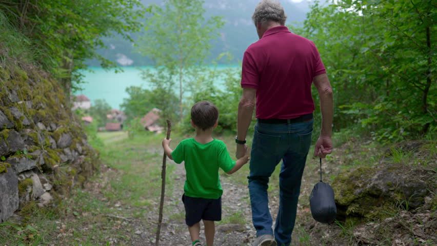 Grandson and Grandfather Walking Hand in Hand on Hiking Trail, Inter-Generational Bonding with Child and Grandpa, Family Connection