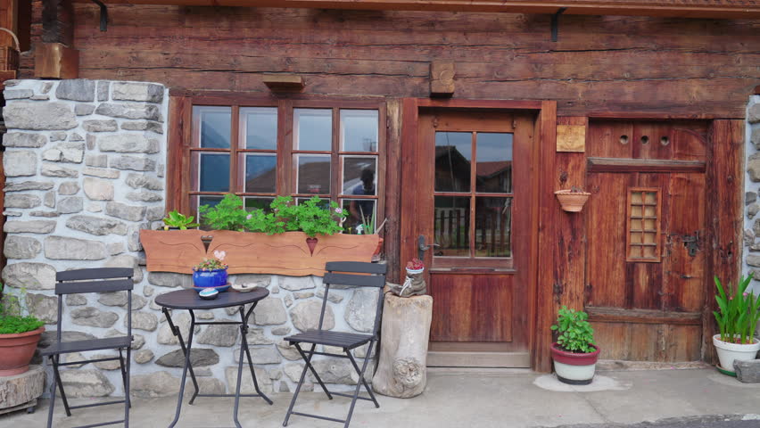 Traditional Swiss rustic wooden facade. Door, windows, and chairs, alpine architecture