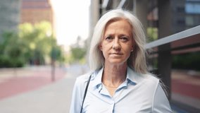 Slow-motion video of a grey-haired businesswoman from serious to smile
