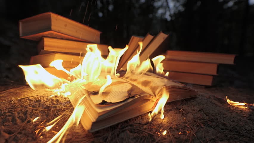An open book is on fire. Big bright flame, burning paper on old publication in the dark. Book Burning - Censorship Concept, slow motion, close-up, 4K Royalty-Free Stock Footage #1107129903