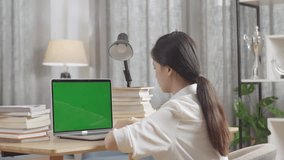 Asian Teenager Learning Online From Laptop With Green Mock Up Screen, Raising Hand Distance Learning Online At Virtual Lesson Class With Teacher Tutor On Laptop By Video Conference Call At Home
