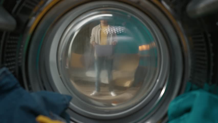 View from inside the washing machine, young man with laundry basket takes out clothes from the drum Royalty-Free Stock Footage #1107131299