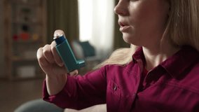 Blonde woman sitting on the sofa, having an asthma attack and using an inhaler, close up shot - Powered by Shutterstock - Get 15% off with code: PIKWIZARD15