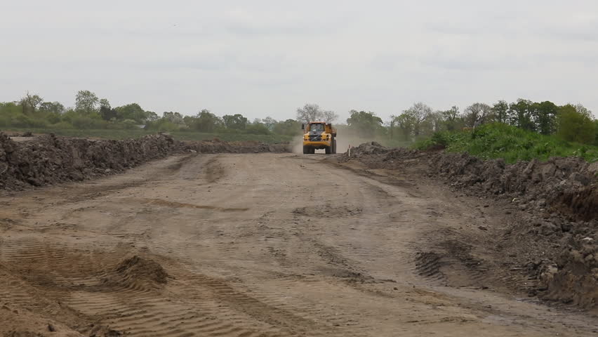 Heavy earth mover approaching kicking up dust