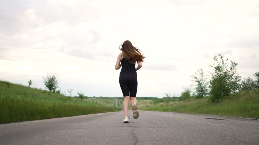 Happy girl athletic walking. Hiking in nature. The girl runs to success. Child winner playing sports on a rural road. Concept of healthy lifestyle. Hiking and running outdoors. Competition winner girl Royalty-Free Stock Footage #1107139665