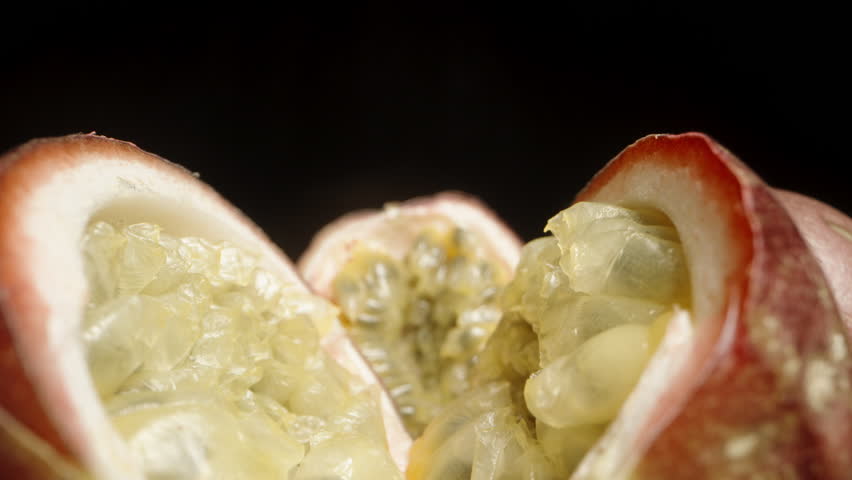 The camera glides forward through two halves of sliced passion fruits. Macro shot.