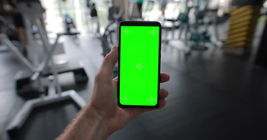 Male hand holding a smartphone with empty green screen chromakey at the gym Royalty-Free Stock Footage #1107144307