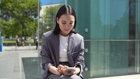 Smiling young Asian business woman holding smartphone using mobile apps tech, happy professional chinese businesswoman making online payment on cell phone reading news sitting on busy big city street. - Powered by Shutterstock - Get 15% off with code: PIKWIZARD15