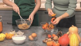 lesbian family cooking together pumpkin pie for thanksgiving holiday dinner meal kitchen decorated fall season. females mixing sugar and butter pealing baked pumpkin glass bowl whisk - Powered by Shutterstock - Get 15% off with code: PIKWIZARD15