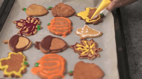 applying royal icing glaze on thanksgiving biscuits maple leaf shape pumpkin form homemade sugar icing glazing squeezing from pastry bag on freshly baked cookies. traditional thanksgiving sweets Video Stok