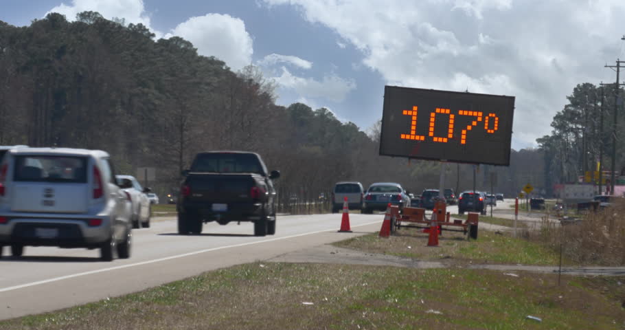 A digital construction site road sign warns passers-by of a heat advisory. Shows the temperature at 107-degrees.	