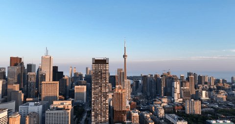 Toronto, Canada, August 3, 2023: Aerial wide-angle pull-out of the cityscape highlighting commercial areas, residential zones, a major landmark, lake backdrop, clear skies, ongoing condo construction. Szerkesztői stockvideó