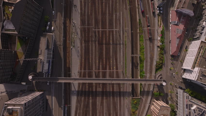 Top down panning footage of trains moving on wide railway yard with multiple tracks and switches. Surrounding buildings with green roofs and vegetation. Zurich, Switzerland