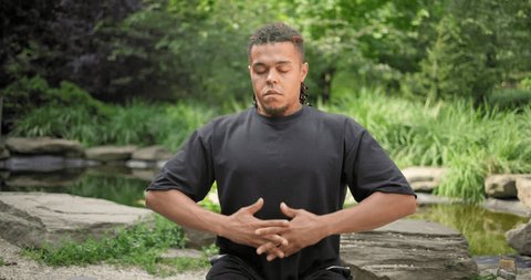 Calm mindful young african american man meditating doing exercise practicing yoga breathing for peaceful mind and zen - Βίντεο στοκ