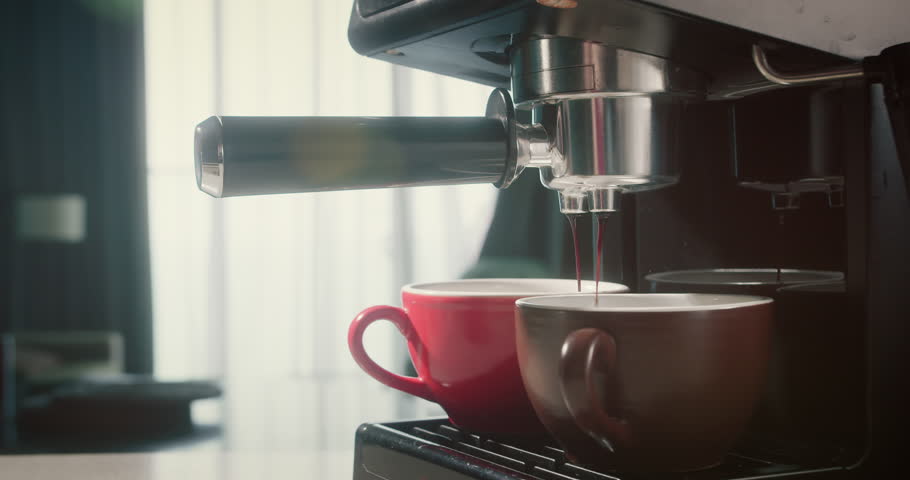 Pouring coffee stream from machine in red and broun cup. Home making hot Espresso. Using filter holder. Flowing fresh ground coffee. Drinking roasted black coffee in the morning. 4K