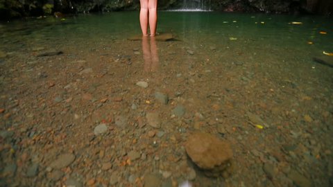 Beautiful woman in small bikini under waterfall in the tropics. Slow Pan Up