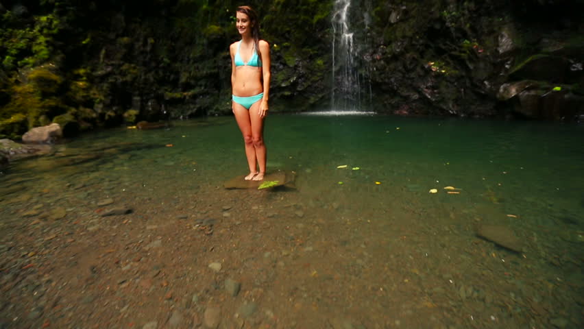 Happy Young Woman Under a Waterfall in the Tropics