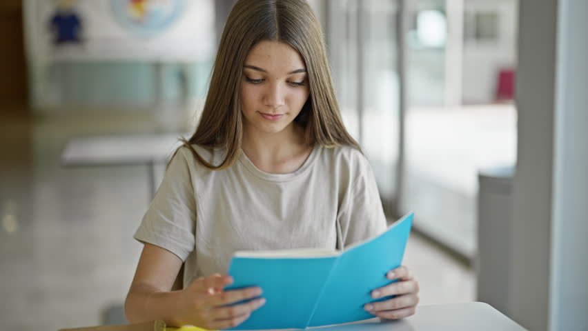 Young beautiful girl student reading book doing thumb up gesture smiling at library Royalty-Free Stock Footage #1107156265