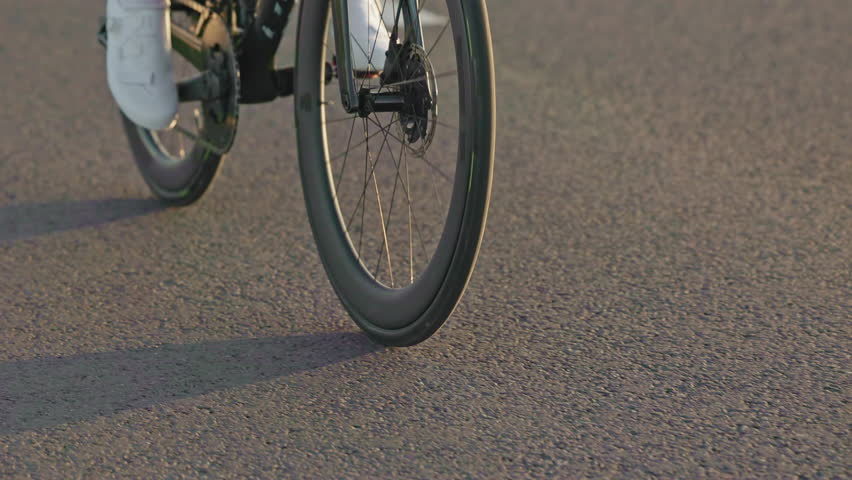 Young rider with professional sports gear increasing cadence while wheeling out of saddle on smooth roadway. Vigorous bicycler rocking bike from side to side while applying equal pressure on feet.