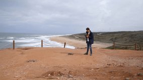 A Young traveller taking off and flying a drone at a Scenic beach of Nazare in Portugal