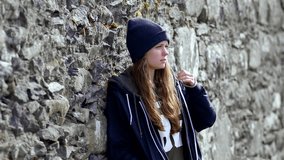 Young woman leaning against a stone wall - slow motion clip 