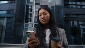 Business Chinese woman standing on the street in the city and texting phone. Shot with RED helium camera in 8K.  